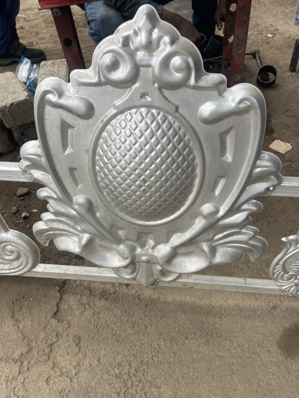 Silver-colour shield-shaped gate flower with a textured oval centre and leaf details