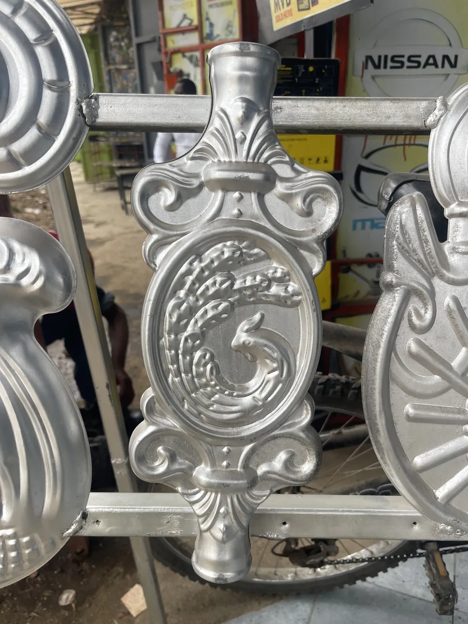 Silver-colour oval gate flower with a raised centre and curled scroll border