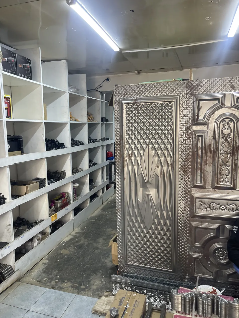 Shelves of gate hardware and decorative metal door panels in a Kenya supply shop